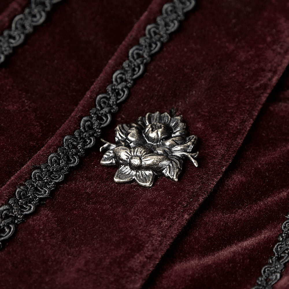 Close-up of a silver ribbon flower embellishment on luxurious burgundy velvet fabric with ornate detailing.