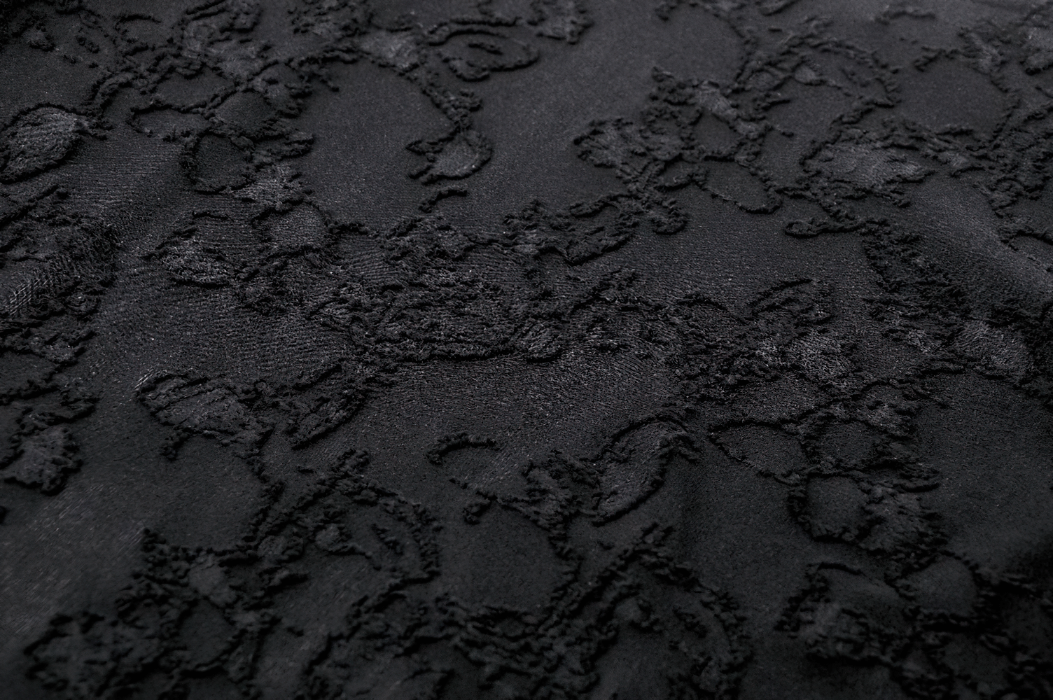 Close-up of elegant black lace fabric with intricate floral patterns, perfect for gothic-inspired fashion.