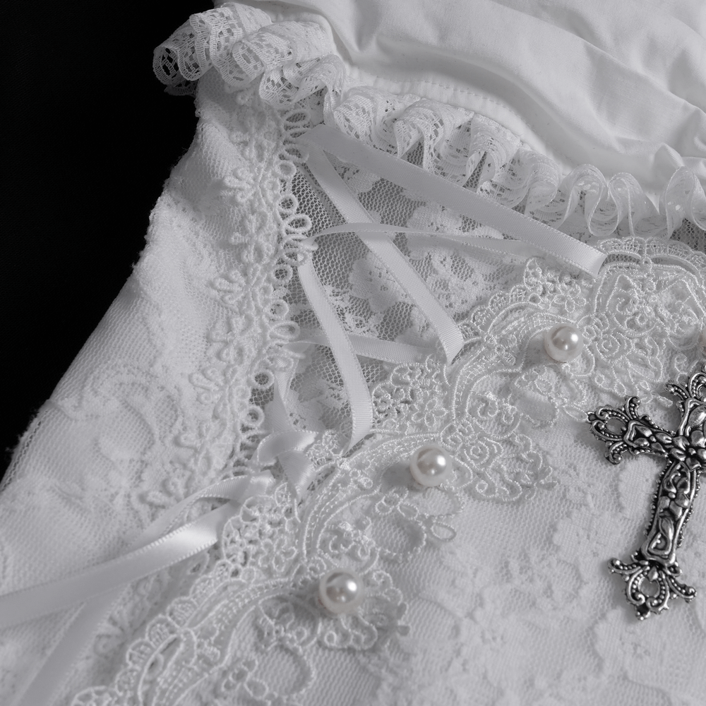 Close-up of elegant white dress detailing with lace, ruffles, pearls, and silver ornament.