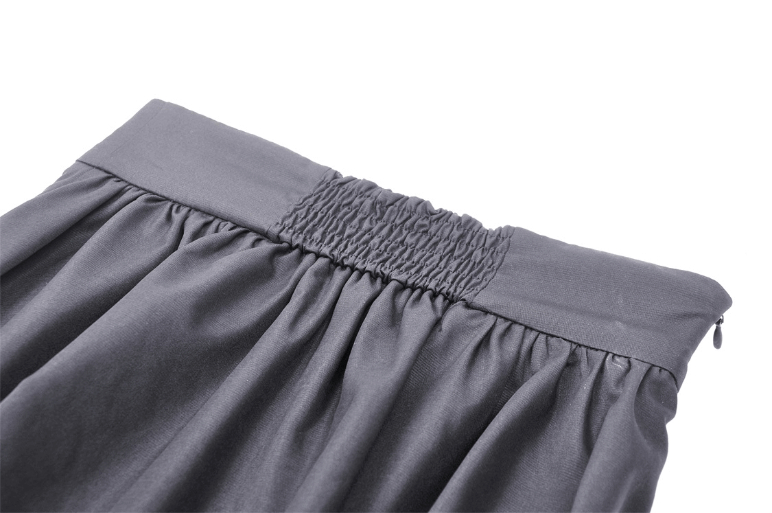 Close-up of the waistband of an elegant black A-line skirt with smocked detailing.