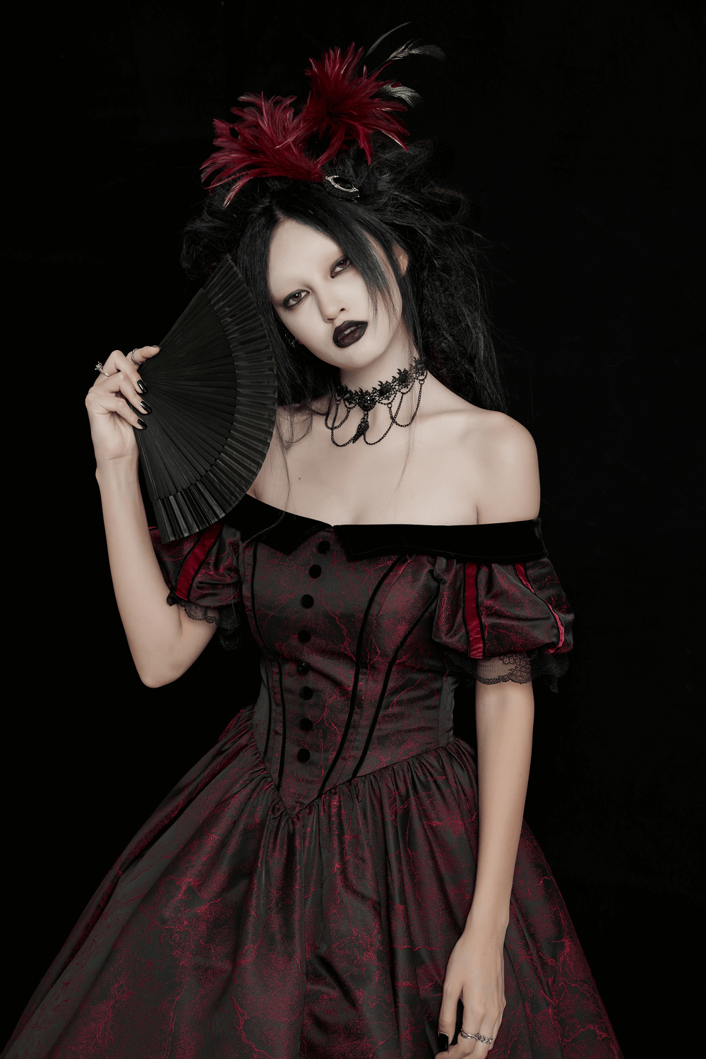 Elegant goth model in off-shoulder Victorian ball gown holding a fan, showcasing dramatic lace and jacquard details.