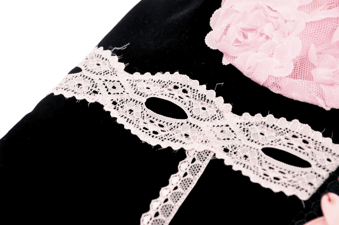 Close-up of elegant black corset top featuring delicate pink lace and floral embellishments.