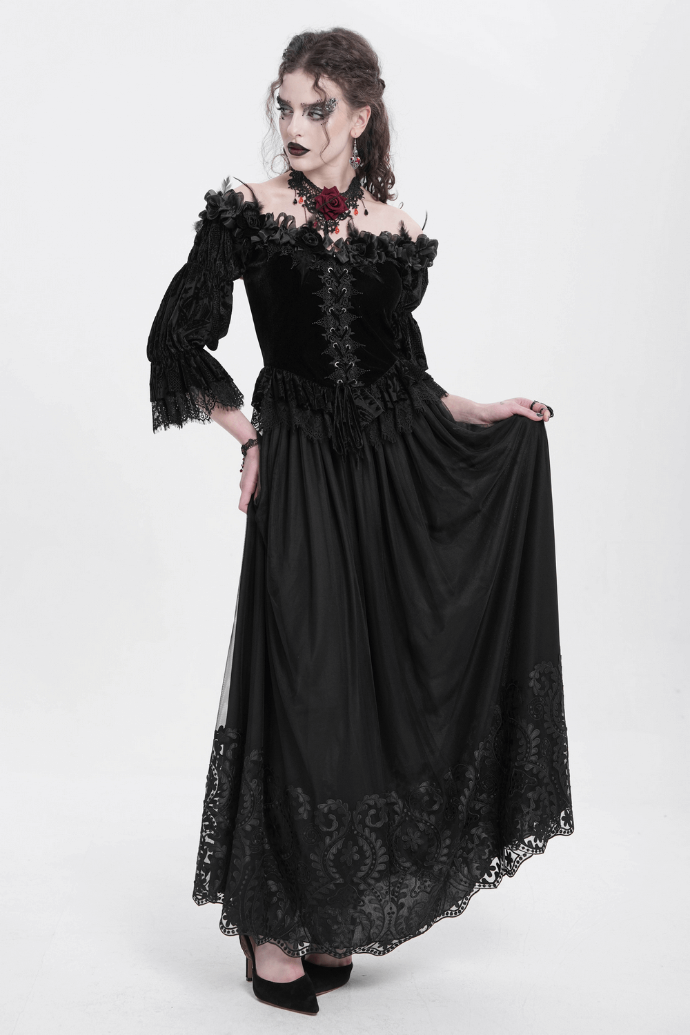 Elegant gothic model in black mesh maxi skirt with embroidered hem and off-shoulder top, showcasing dark romantic fashion.