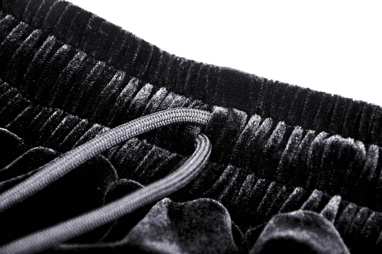 Close-up of black velvet fabric with elastic waistband and drawstring detail for stylish comfort.