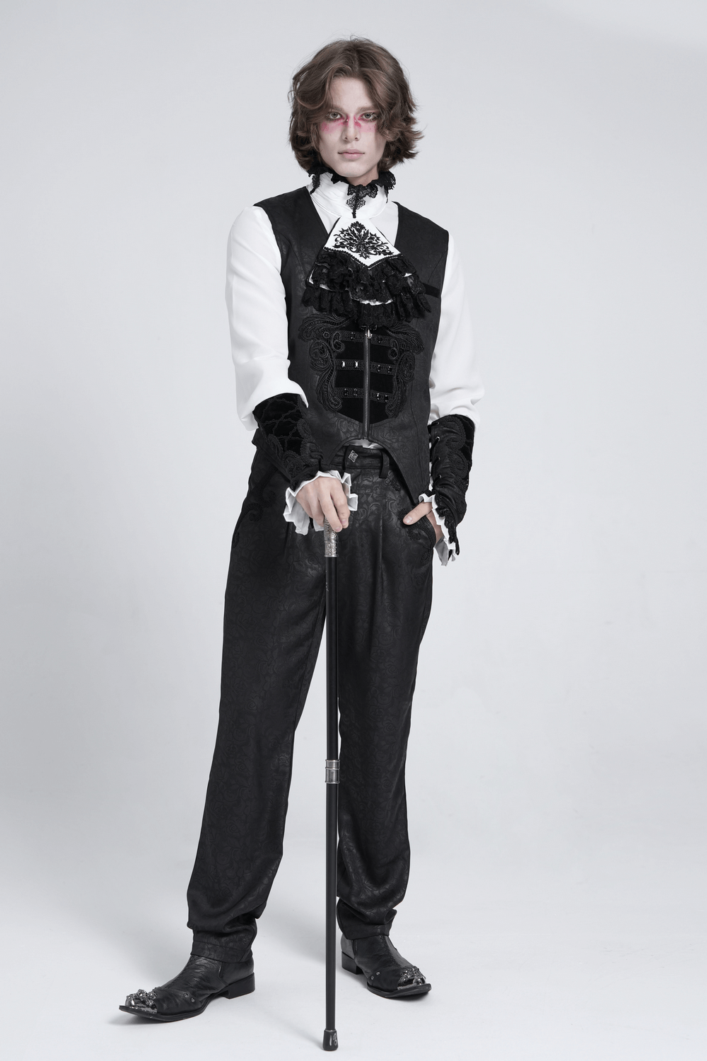 Gothic fashion model in elegant black and white aristocratic outfit with cane, exuding dark romantic flair.