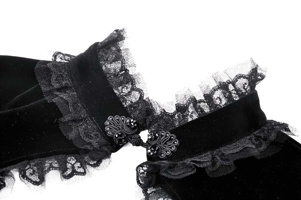 Close-up of an elegant black velvet bolero with intricate lace trim and decorative buttons.