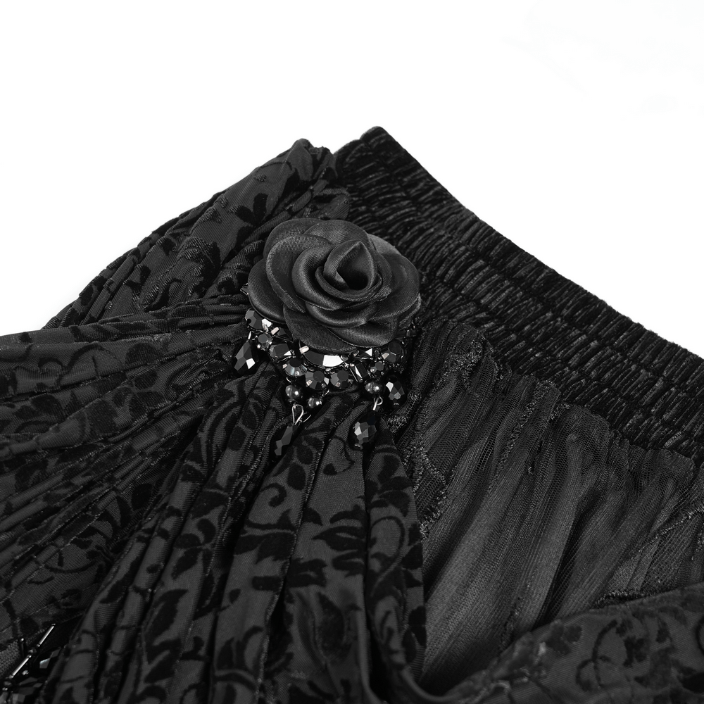 Close-up of elegant black velvet skirt with lace, beaded rose detail, showcasing gothic floral embroidery and dramatic design.