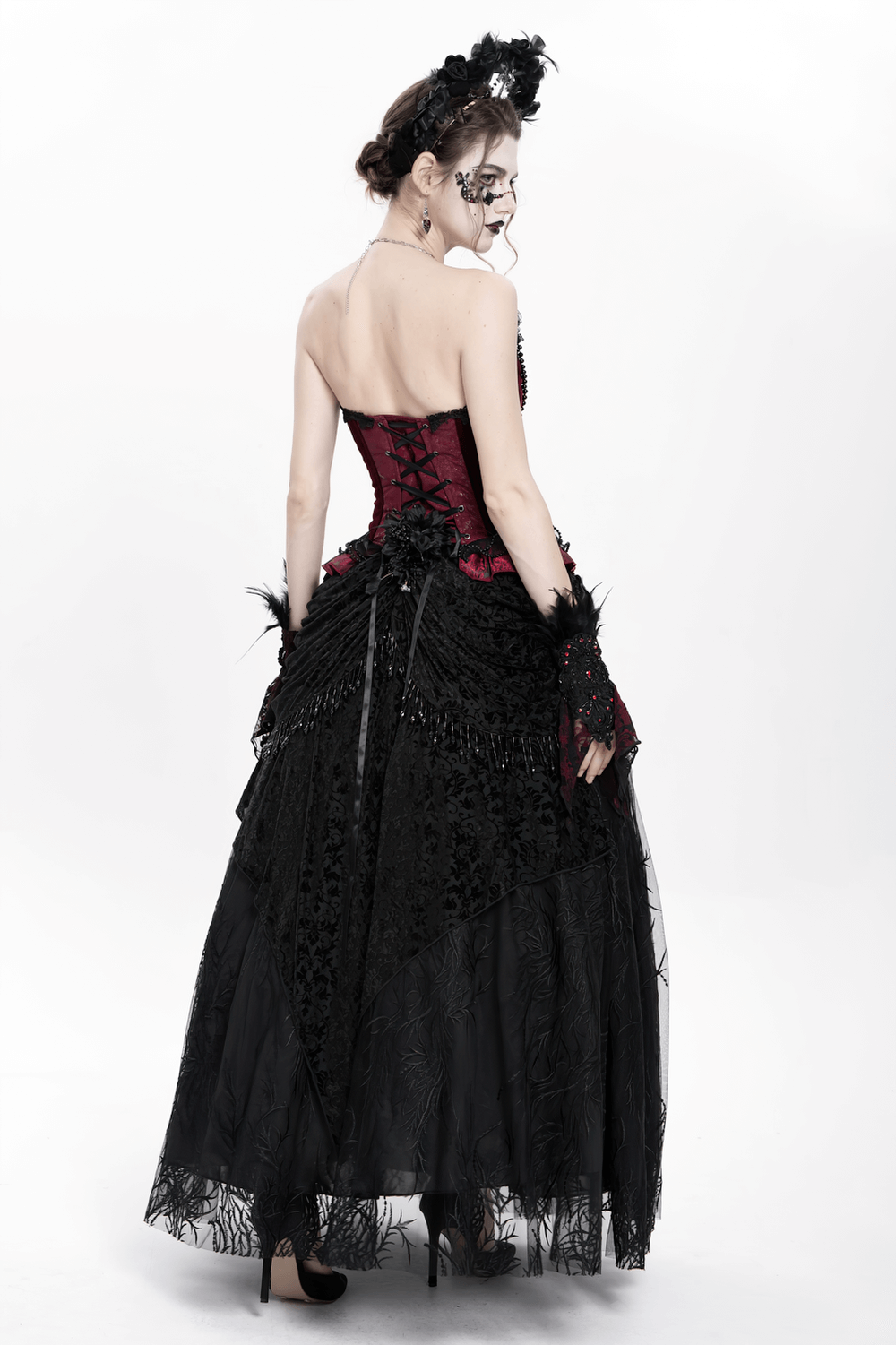 Elegant gothic woman in black velvet lace skirt with floral embroidery and beaded drapes, showcasing a romantic Victorian style.