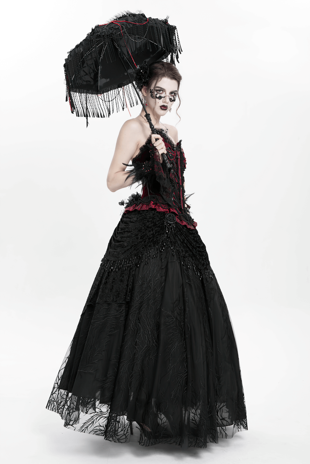 Elegant model wearing a black corset and layered maxi skirt with a parasol, showcasing gothic fashion and intricate details.
