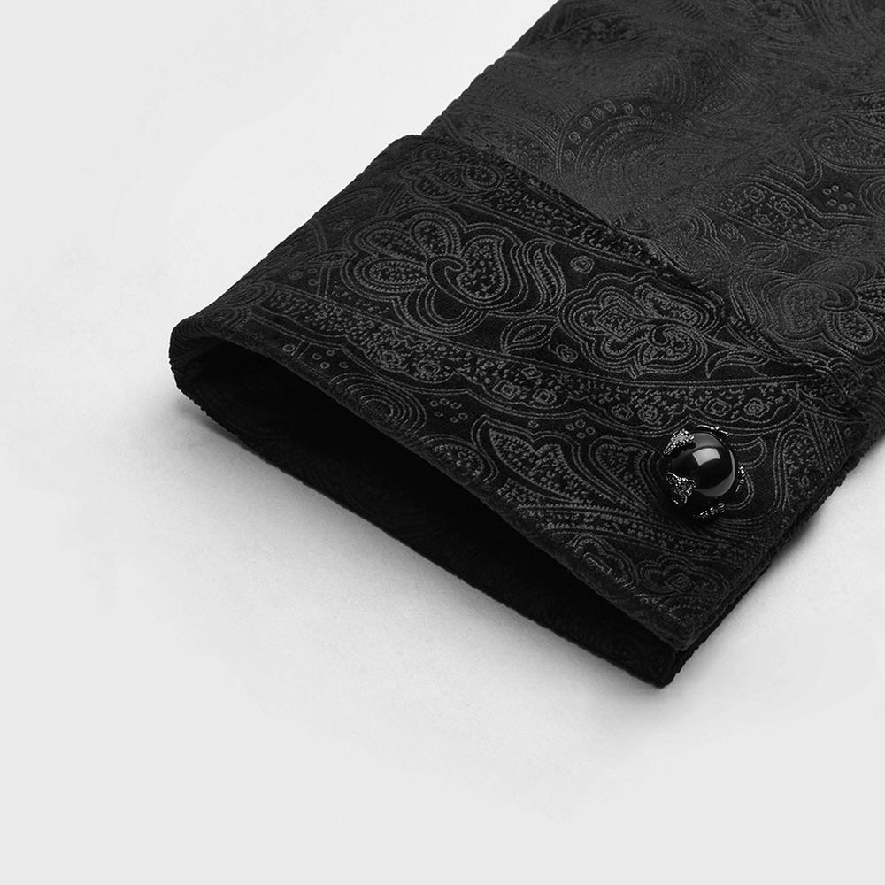 Close-up of an elegant Gothic gentleman's shirt cuff with intricate black printed fabric and a gemstone button.