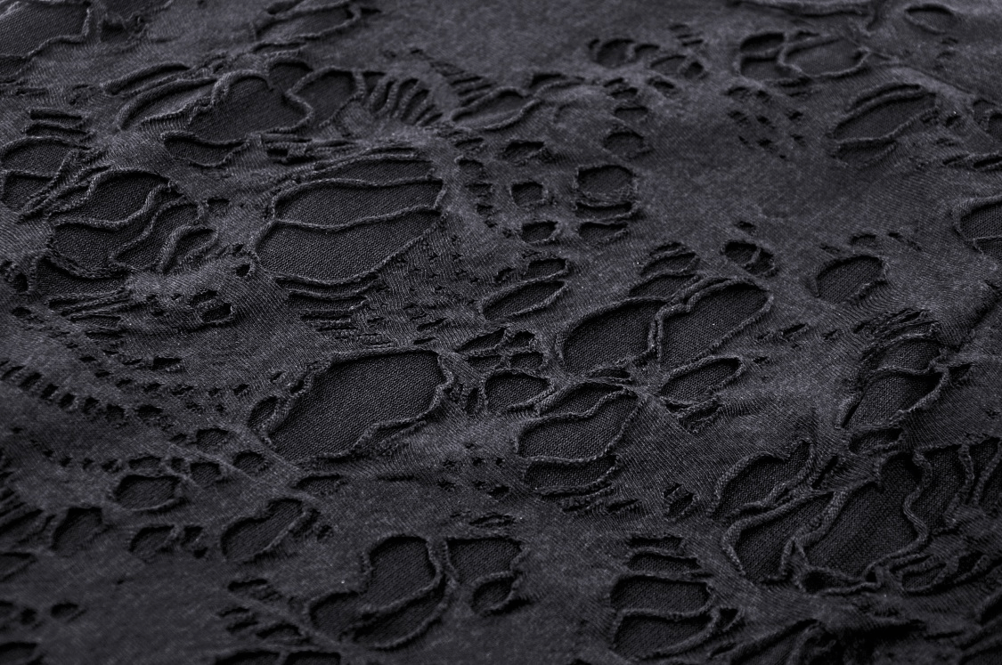 Close-up of intricate black lace fabric with edgy ripped details, perfect for gothic fashion.