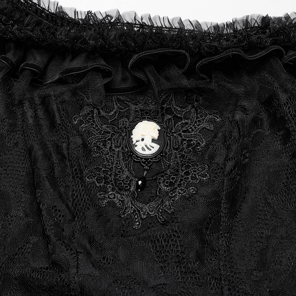 Close-up of elegant black lace detailing with a cameo brooch on a Gothic dress, showcasing intricate textures.