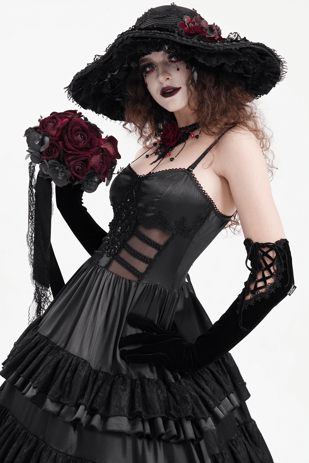 Elegant gothic model in black ruffle maxi dress with hat and roses, showcasing Victorian-inspired style.