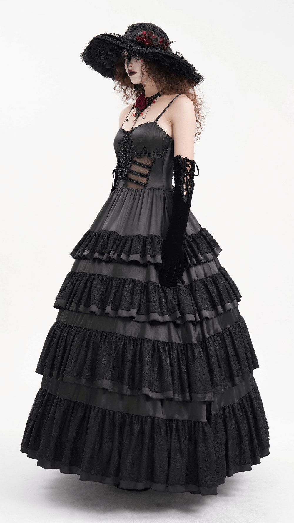 Elegant gothic black lace tiered ruffle maxi dress with straps, worn by a woman in a dramatic hat and gloves.