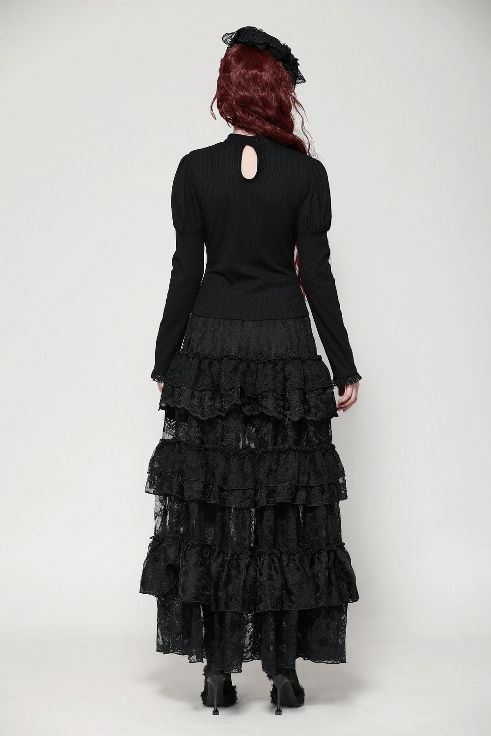 Woman in elegant black gothic lace top and ruffled skirt, showcasing Victorian-inspired design from the back.