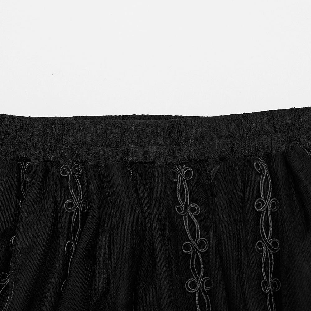 Close-up of the elastic waistband and intricate 3D floral embroidery on a sheer black gothic maxi skirt.