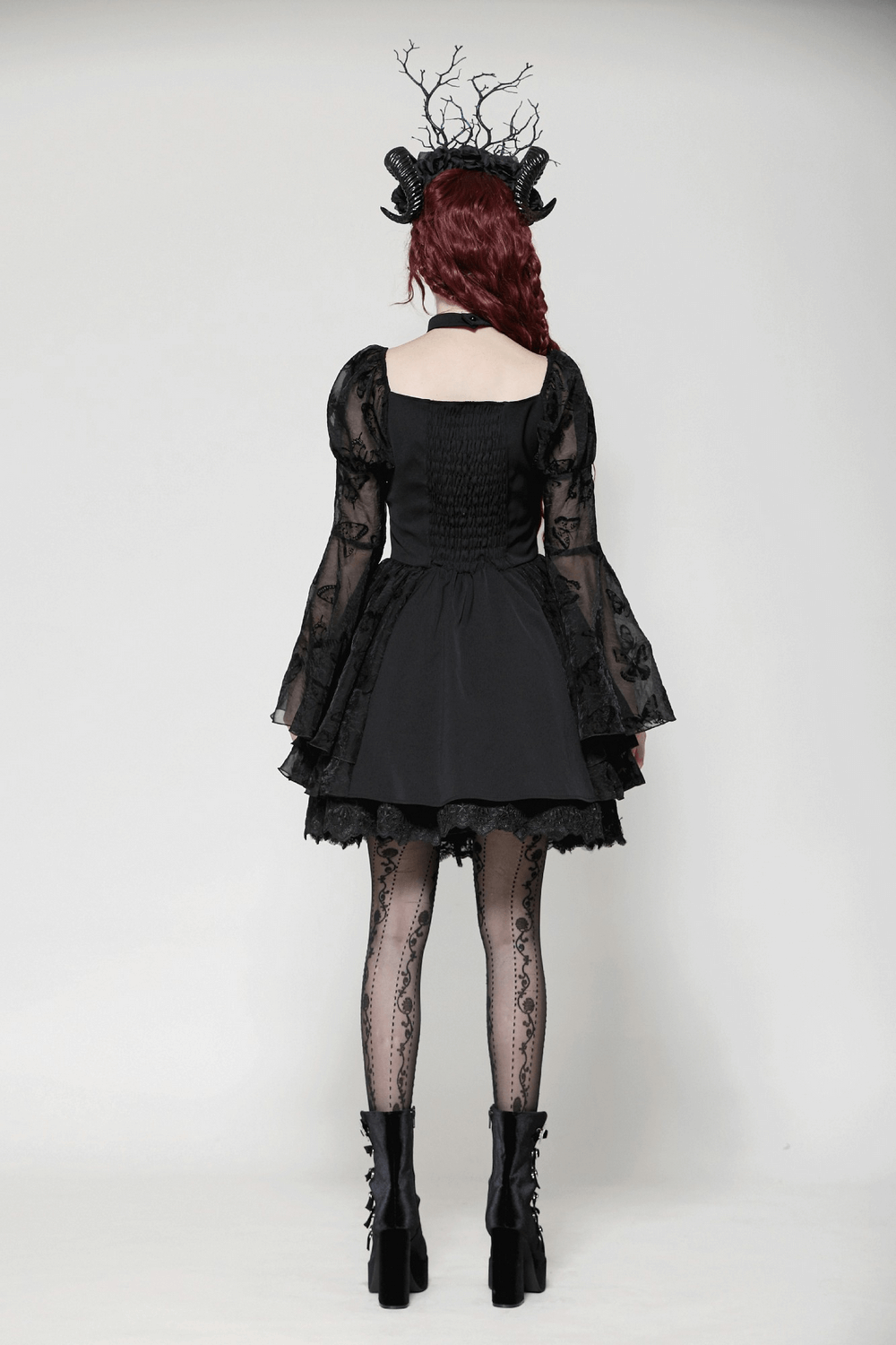 Back view of a woman in an elegant gothic mini dress with butterfly accents and big lace sleeves.