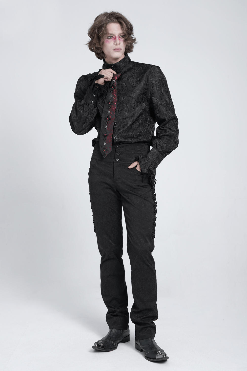 Gothic fashion model in a black patterned shirt and red-black floral crystal necktie, stylishly showcasing alternative attire.