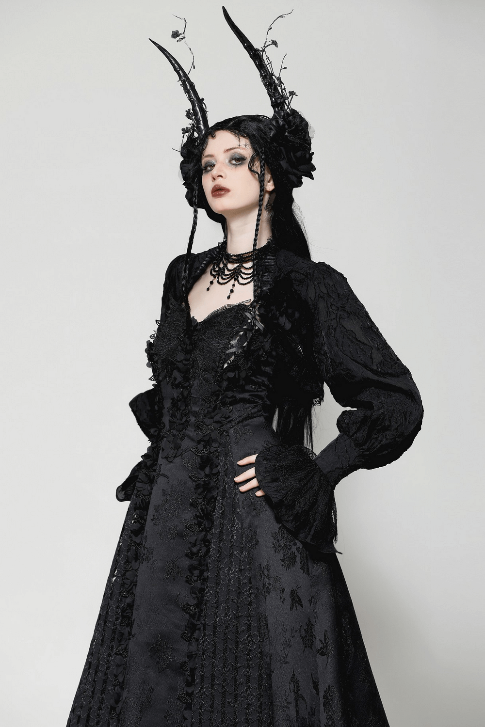 Elegant gothic black dress with ruffled sleeves, adorned with floral lace and dramatic horns, exuding Victorian charm.