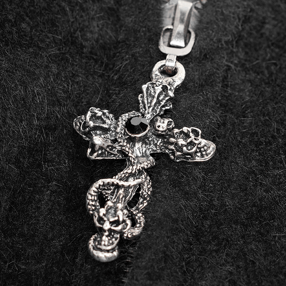 Intricate gothic silver cross pendant with snake and floral motifs on dark velvet background.