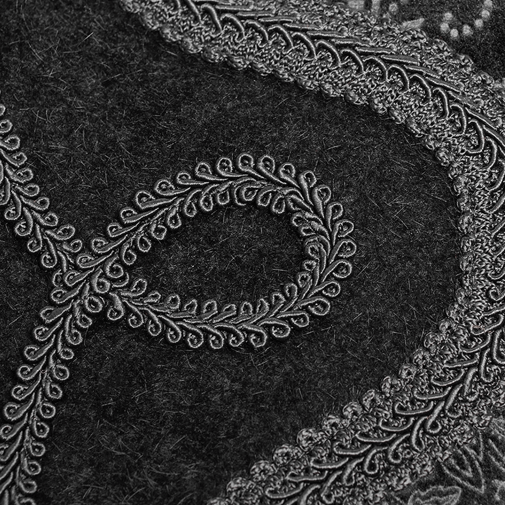 Close-up of embossed paisley detail on elegant Gothic velvet fabric, showcasing intricate black and silver patterns.