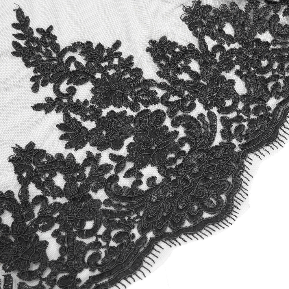 Close-up of intricate black lace detailing on a gothic skirt, showcasing elegant floral patterns.