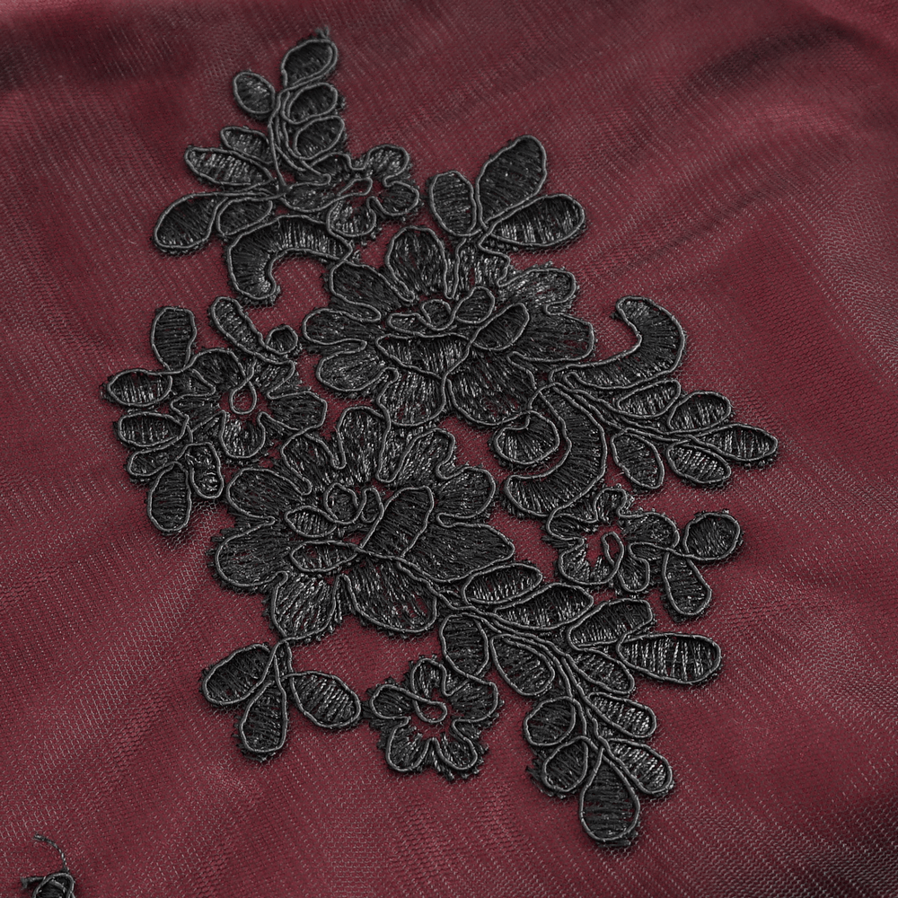 Intricate black lace floral embroidery on a rich burgundy fabric.