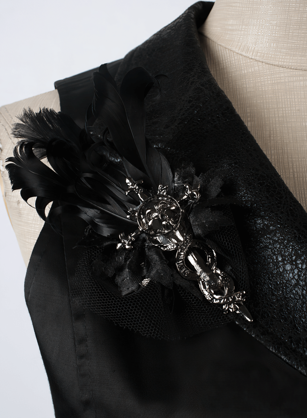 Close-up of an elegant black waistcoat featuring a decorative black feather brooch, perfect for gothic fashion.