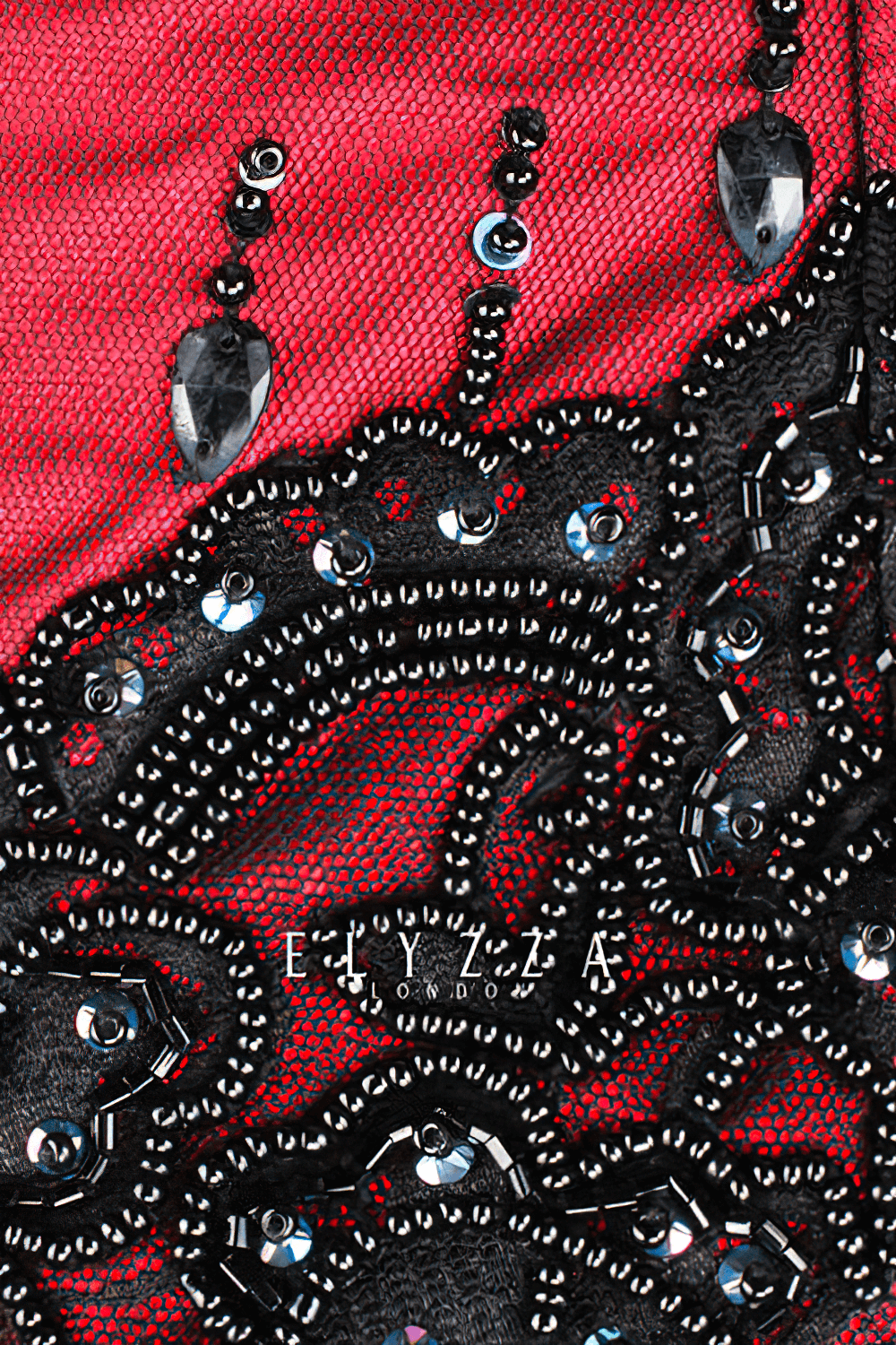 Close-up of intricate beadwork and lace detailing on a red gothic Victorian corset, showcasing elegance and craftsmanship.