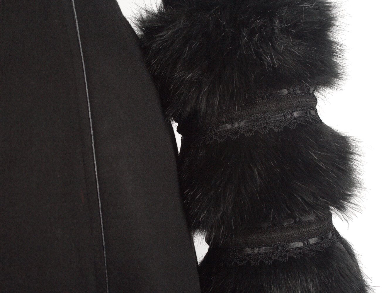 Close-up of black hooded coat with luxurious faux fur cuffs and elegant lace detailing.