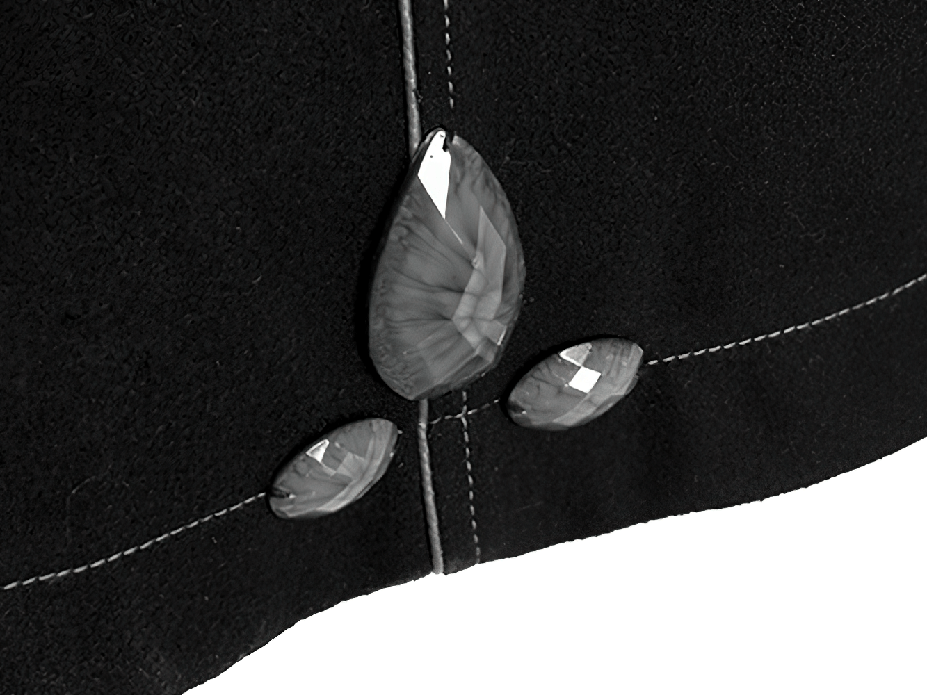 Close-up of black coat detailing with three elegant faux gems on the fabric, adding a gothic flair.