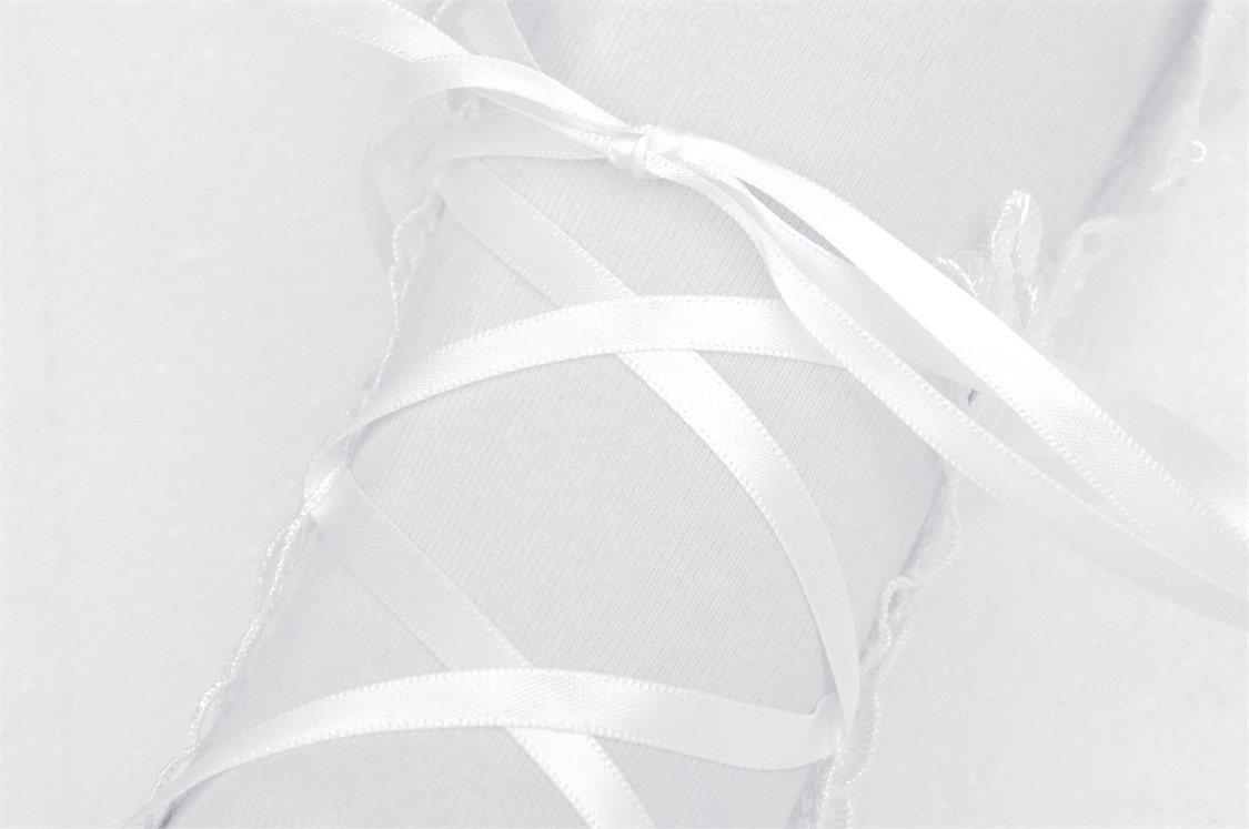 Close-up of a wedding gown sleeve with elegant white ribbons beautifully laced for a chic bridal look.