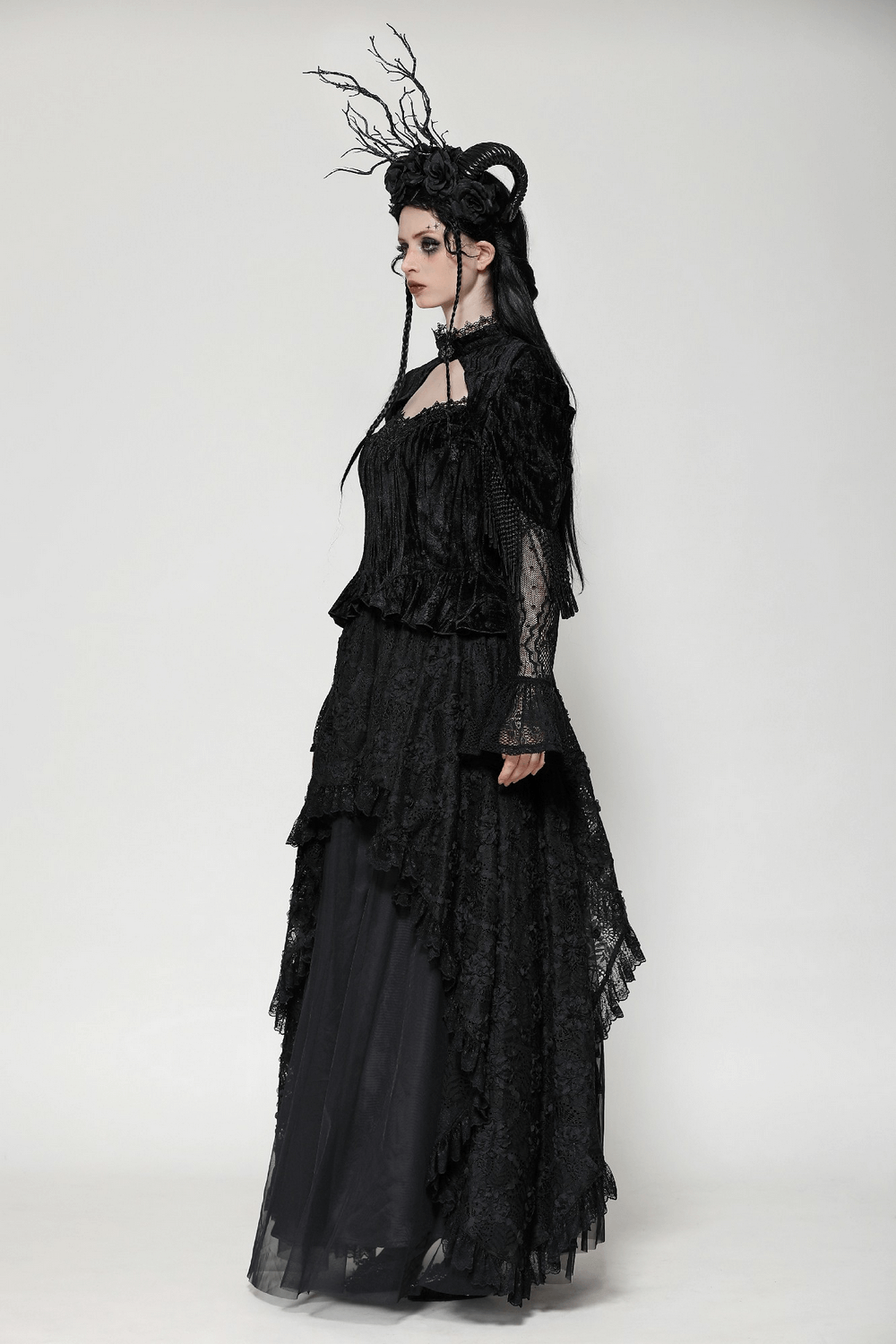 Elegant gothic woman in layered black lace maxi skirt with asymmetrical hemline and unique headpiece. Perfect for formal occasions.