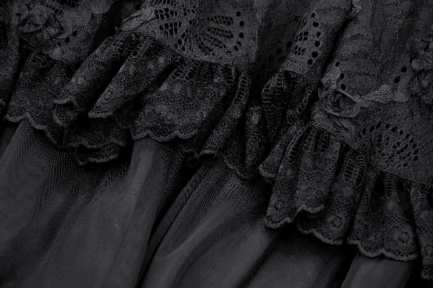 Close-up of elegant black lace layered skirt showcasing intricate lace details and flowing fabric. Perfect for gothic chic fashion.