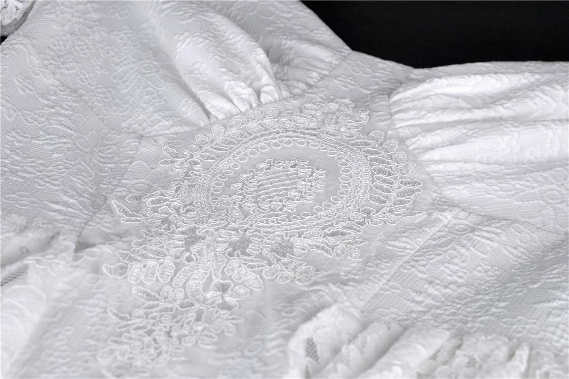 Close-up of intricate white lace detailing on an elegant off-shoulder dress with boho chic vibes.