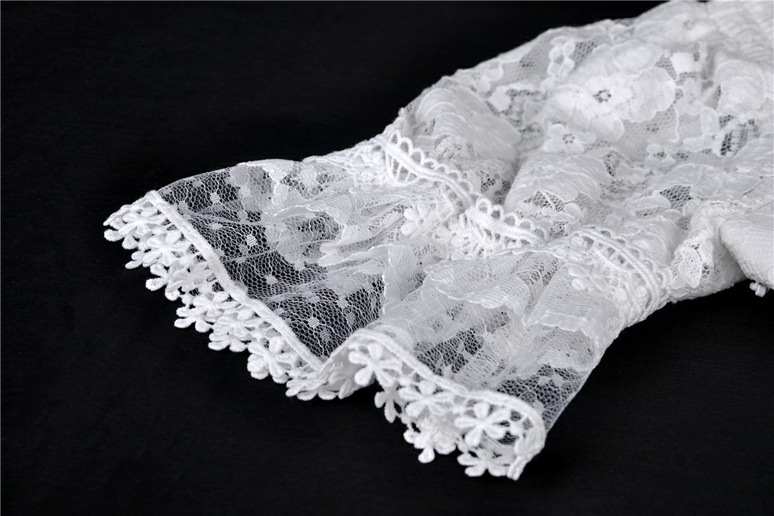 Close-up of elegant white lace detailing on off-shoulder dress with intricate floral patterns and frilled hem.