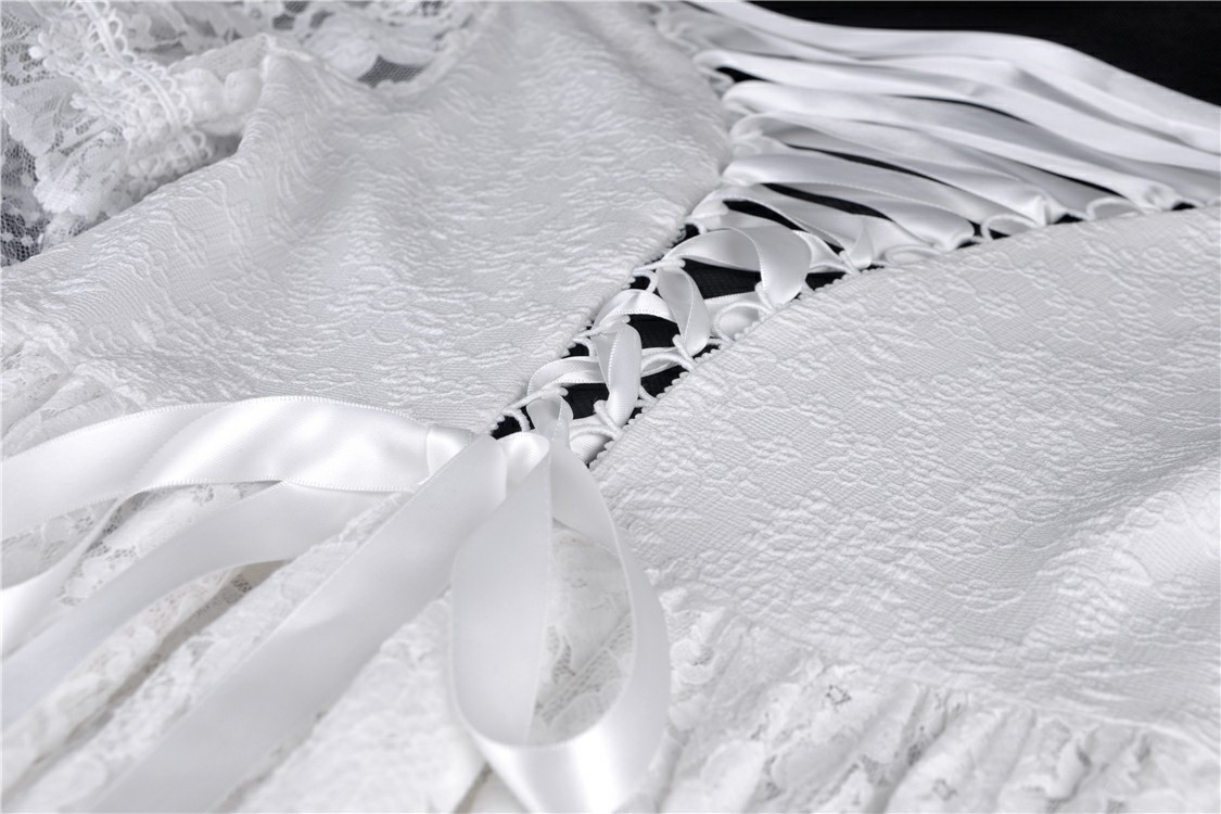 Close-up of elegant white lace dress detail with delicate ribbons and intricate lace patterns for a chic look.