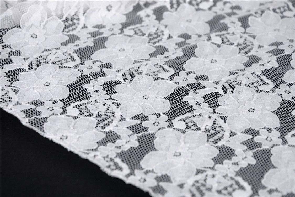 Close-up of elegant white floral lace fabric, perfect for off-shoulder dresses and boho chic designs.
