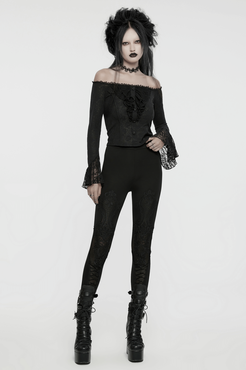 Woman in elegant off-shoulder gothic lace top with ruffles and black leggings, exuding dark elegance and style.