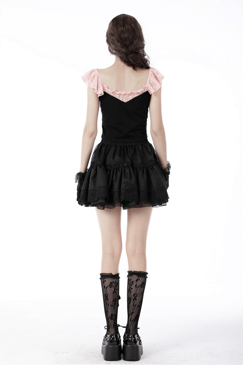 Back view of an elegant black crop top with pink lace and bow detail, paired with a black flared skirt and stylish boots.