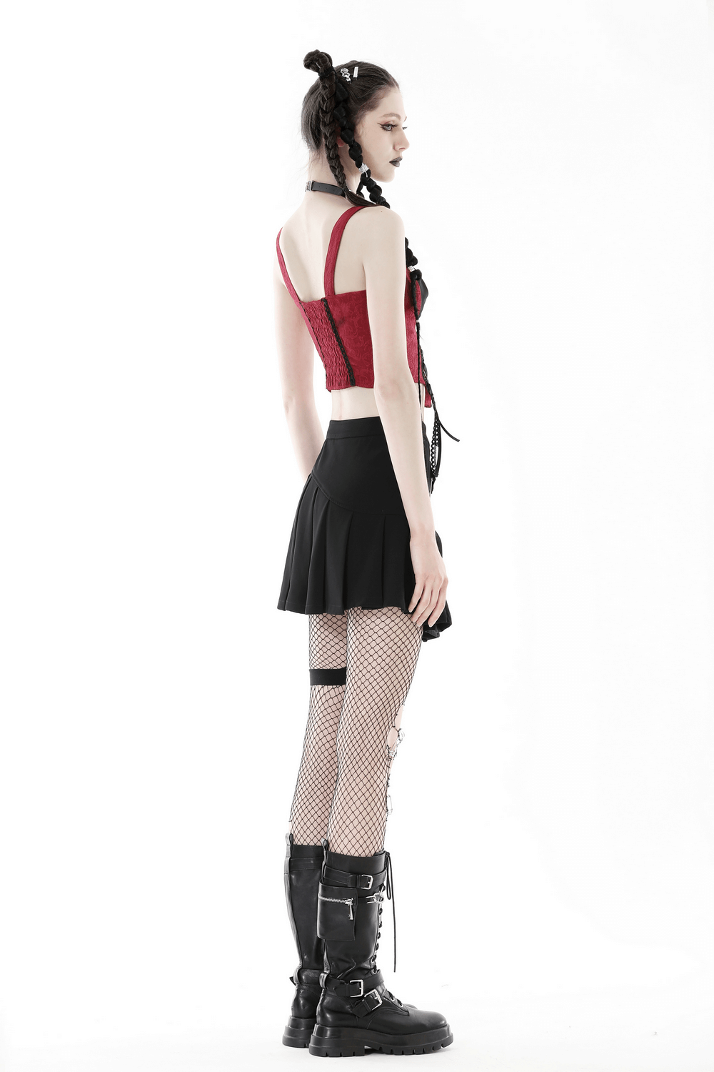 Model wearing a burgundy lace-up corset with black accents, paired with a black skirt and combat boots, showcasing a gothic style.