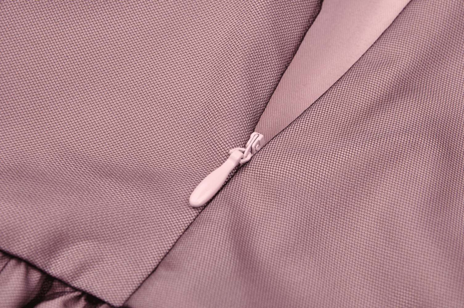 Close-up of the zipper detail on a stylish lace-up dress in soft pink fabric.