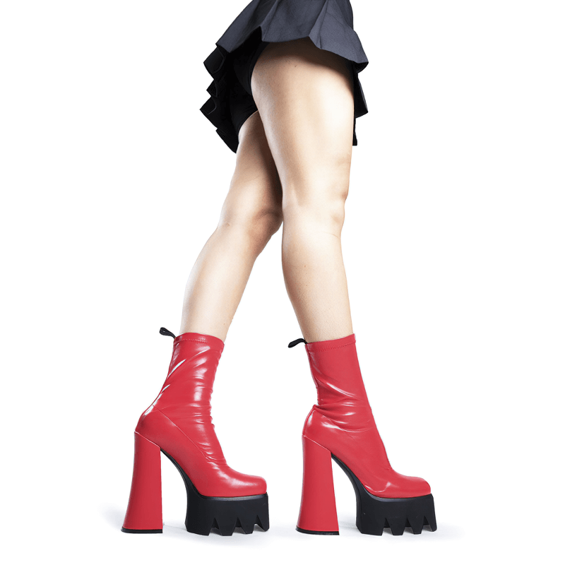Bold red high heel platform boots showcasing stylish legs in a playful, grunge aesthetic.