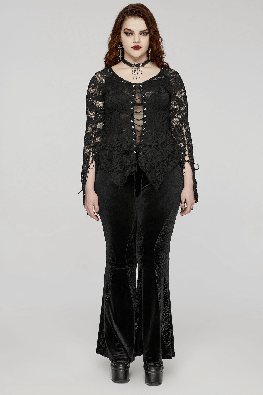 Chic woman in black lace long-sleeve top and flared velvet pants, showcasing a gothic style with alluring details.