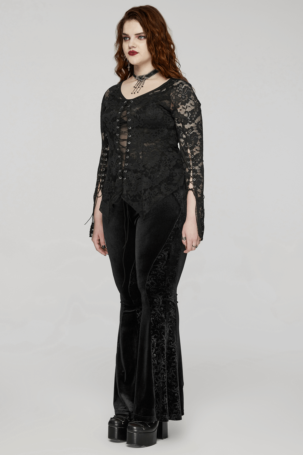 Chic woman wearing an elegant black long-sleeve lace top with button details, paired with stylish velvet flared pants.
