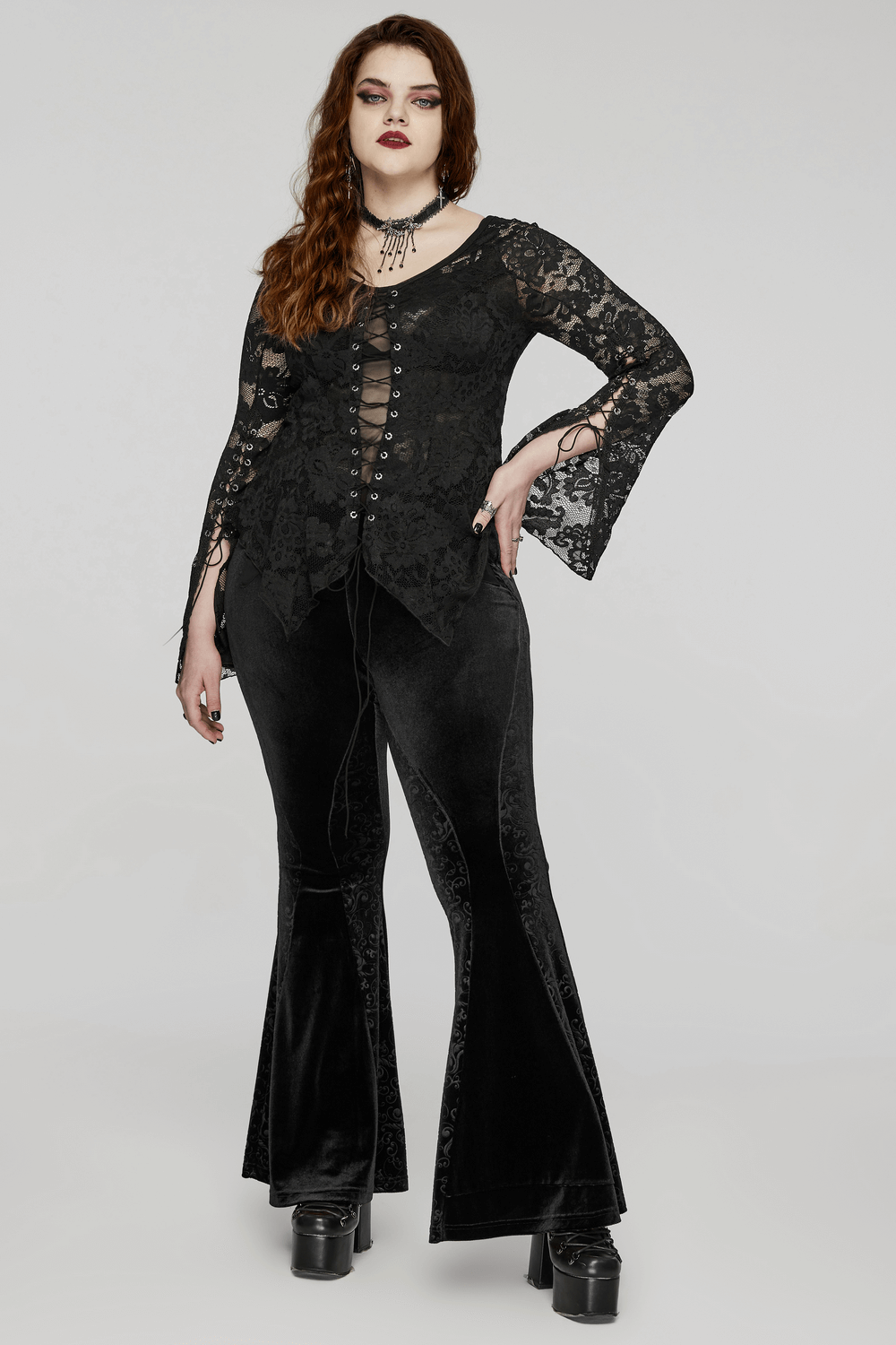 Elegant long-sleeve black lace top on model, paired with bell-bottom pants and stylish platform boots.
