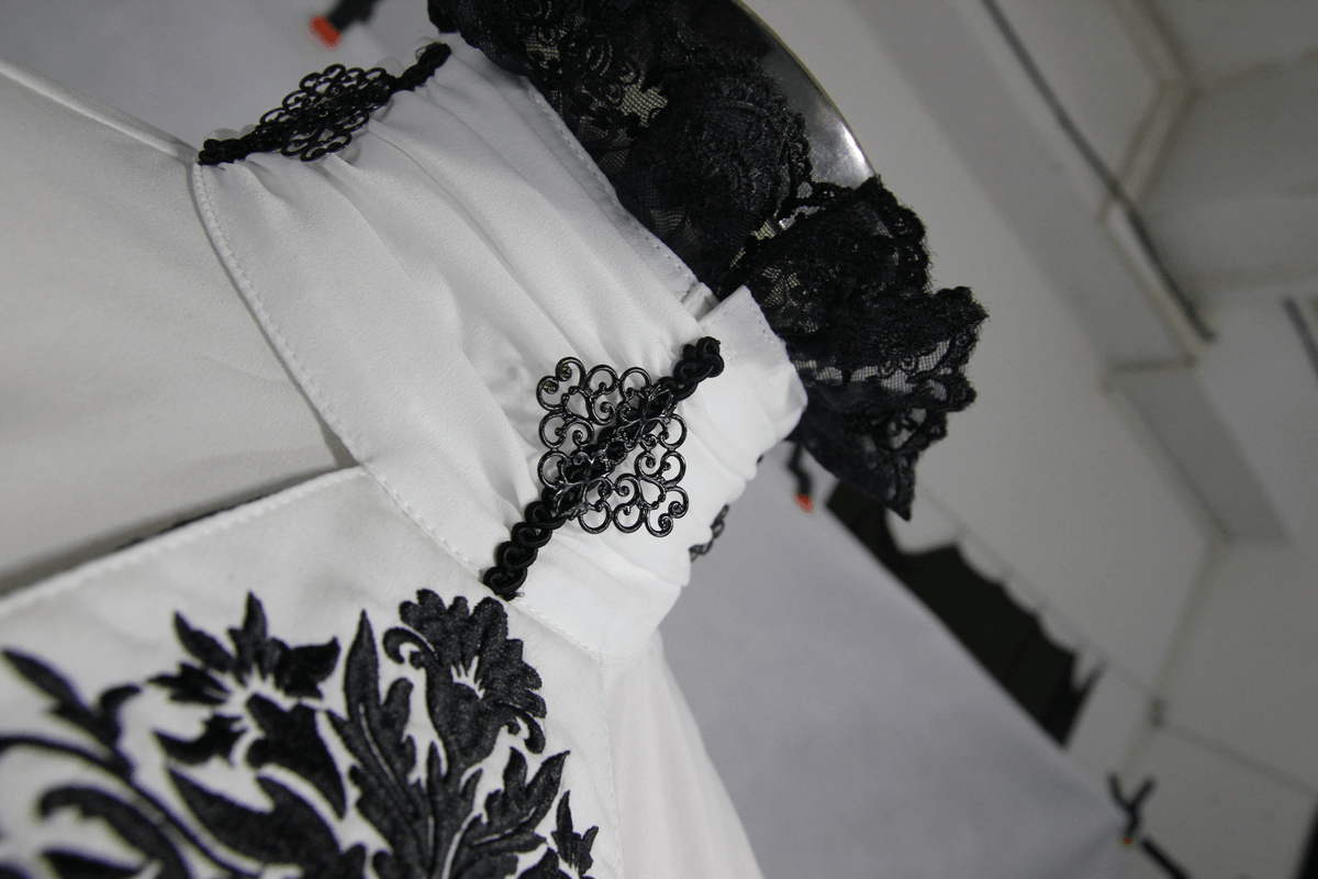 Close-up of a vintage men's gothic shirt in white with black lace details and intricate patterns.