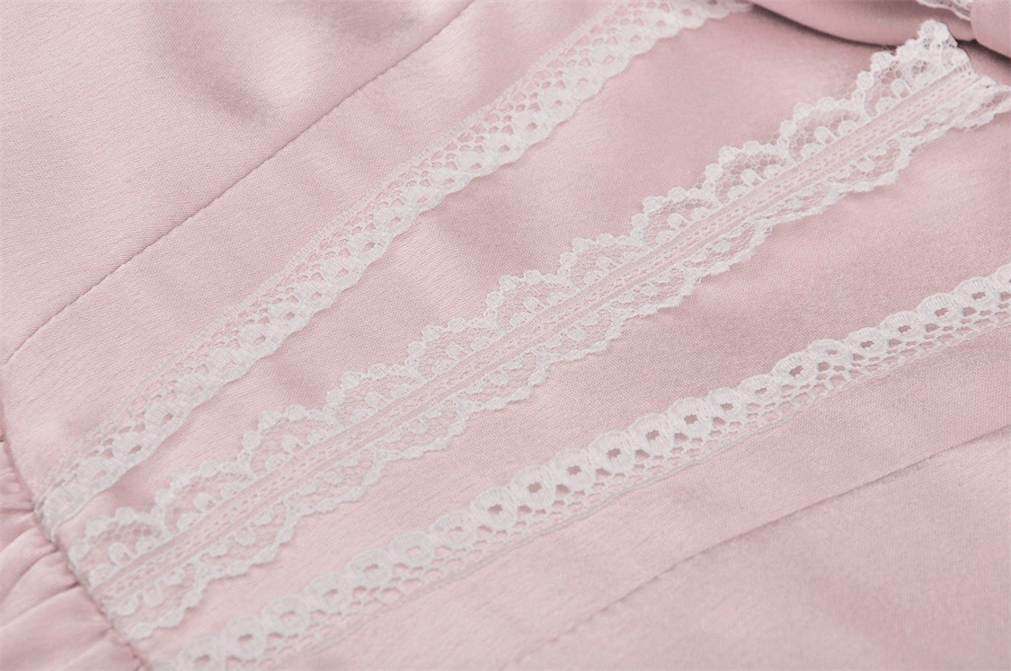 Close-up of soft pink satin fabric with delicate lace detailing for elegant dress design.