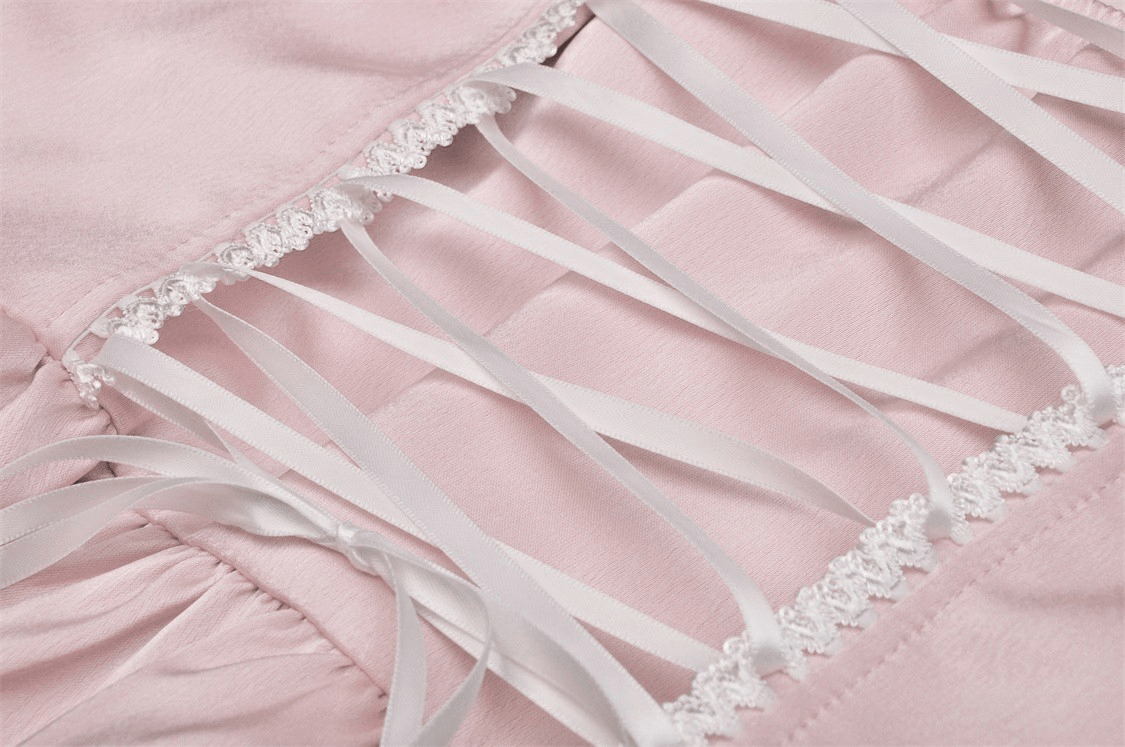 Close-up of the intricate pink satin dress detailing featuring soft satin fabric and delicate white ribbons.