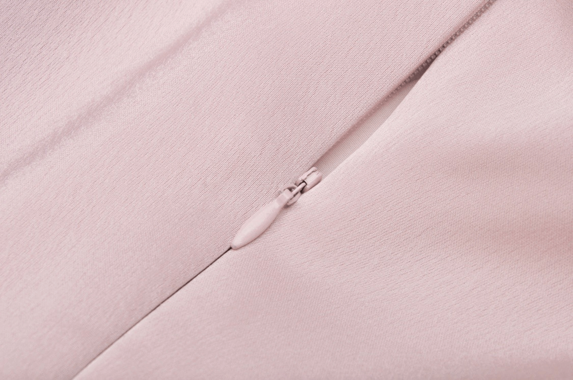 Close-up of the elegant pink satin fabric and zipper detail of a chic A-line dress for evening events.